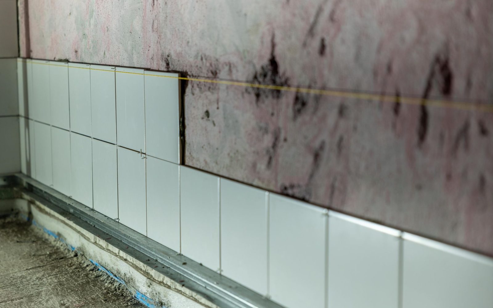 Wandfliesen werden in einem Rohbau-Bad Reihe für Reihe angesetzt