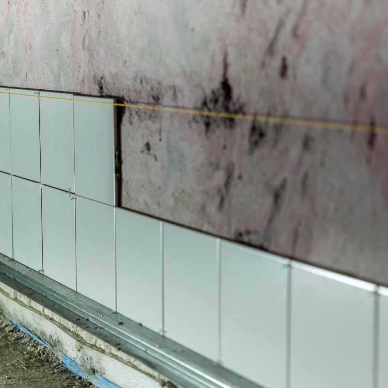 Wandfliesen werden in einem Rohbau-Bad Reihe für Reihe angesetzt