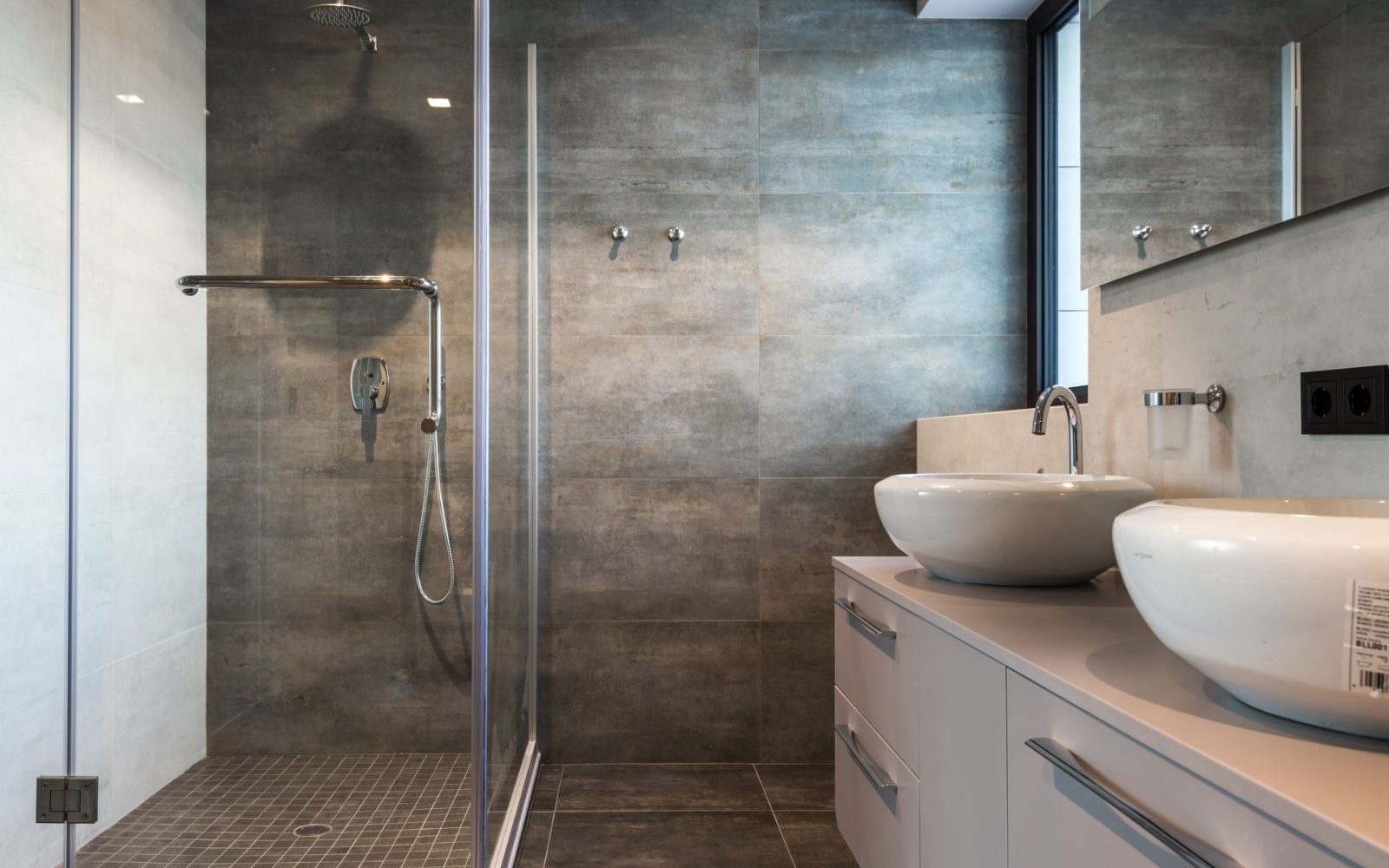Bad mit schiefergrauen Wandfliesen, Dusche und Doppelwaschtisch